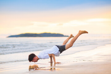 Fototapeta na wymiar Teenager doing calisthenics exercise. Beach yoga.