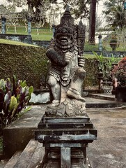 Traditionelle, in dunklen Stein gehauene Wächter-Dämonenstatue in einem Bali-Tempel 