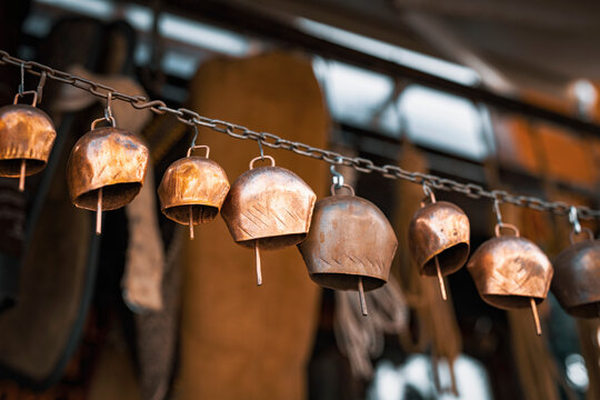 Group of copper cowbells hunged on a rusty chain at antique bazaar.