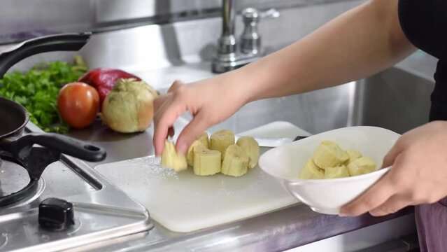 close-up of a latin woman's hands putting the plantains in a plate to fry them.