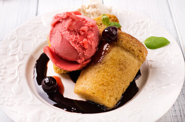 Traditional French rhum baba with cherry ice cream and amarena sauce served as close-up on a classic design plate