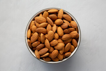 Raw Organic Almonds in a Bowl on a gray background, top view.