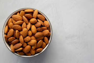 Raw Organic Almonds in a Bowl on a gray background, top view. Copy space.