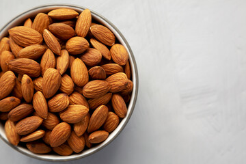 Raw Organic Almonds in a Bowl on a gray background, top view. Copy space.