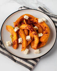 Baked pumpkin slices with spices and cubes of feta cheese. Pumpkin dishes.