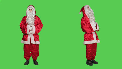 Saint nick person in festive red suit laughing over full body greenscreen, posing as seasonal main character during winter celebration. Adult portraying santa claus with white beard and hat.