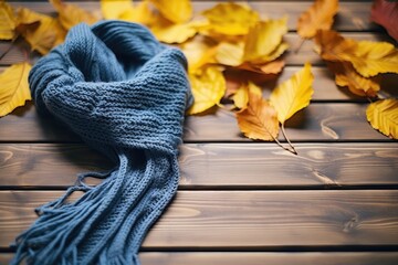 Fototapeta na wymiar Knit scarf against a wooden background, surrounded by leaves - Cozy Autumn Vibe - AI Generated