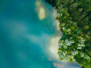 Aerial drone top down view of lake among forest with beautiful turquoise water in summer day. 