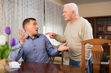 Elderly father is dissatisfied with his adult son. High quality photo