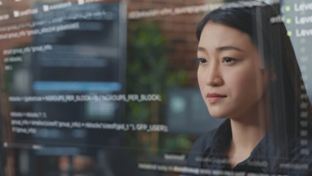 Skilled asian programmer using AR technology to visualize script, writing code on computer screen while in office using Java programming languages. Developer working on fixing database errors