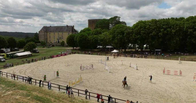Aerial view. Cinematic slow motion close up of young female horsemanship master dressed in a professional apparel is practising exercises for competition of horse racing. Show jumping horse