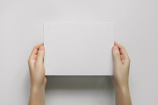 female hands holding a blank white canvas on a grey background