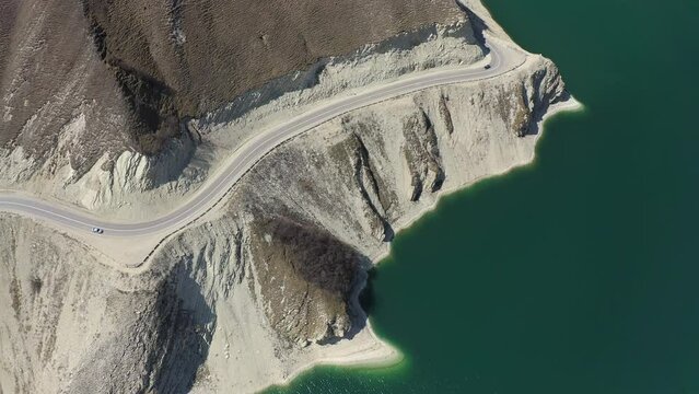 Aerial: mountain road stretches along the shore of an alpine lake