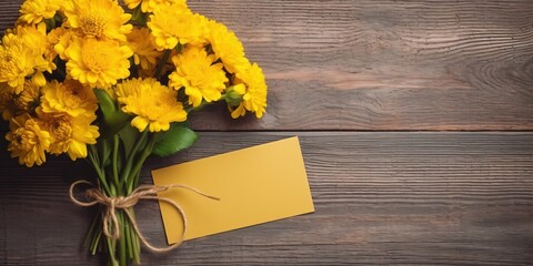 Bouquet of yellow flowers with blank paper card as a tag for name or greetings on wooden background