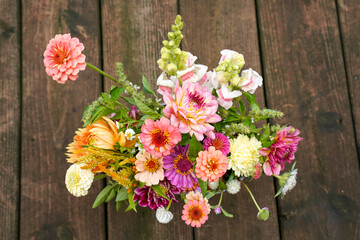 A look down on to the tops of flowers in a bucket. Buckets sits on a wooden deck.