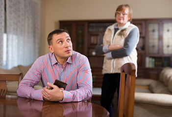 Senior woman scolding her adult son at living room