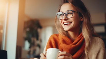 Foto op Plexiglas Portrait of joyful young woman enjoying a cup of coffee at home. Smiling pretty girl drinking hot tea in winter. Excited woman wearing spectacles and sweater and laughing in an autumn day © Roma