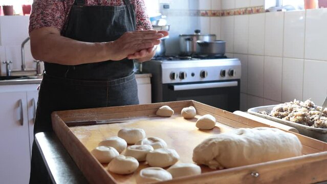 Candid scene of Unidentified Latina Woman Crafting Dough with Hands in Rustic Home Kitchen