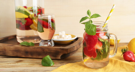 Mason jar of fresh lemonade with strawberry on wooden table