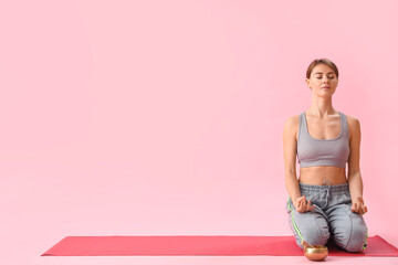 Young woman with Tibetan singing bowl meditating on pink background