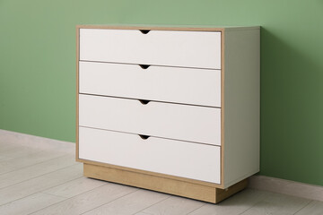 White chest of drawers near green wall in room, closeup