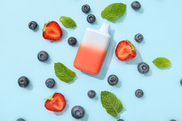 Electronic cigarette with blueberry, strawberry and mint in water on blue background