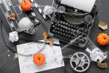 Typewriter with clapperboard, storyboard, film reel and Halloween decor on grunge grey background