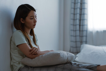 A depressed woman sitting in the bedroom