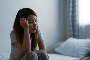 A depressed woman sitting in the bedroom
