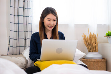 Asian woman using a laptop working long-distance at home 