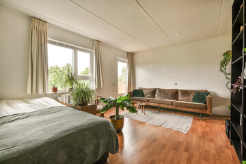 a living room with wood flooring and a couch in the center of the room there is a large window that looks out into