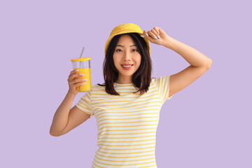 Beautiful Asian woman with glass of juice on lilac background