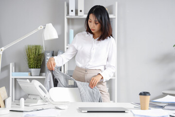 Young Asian businesswoman with cup of coffee working in office
