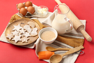 Composition with tasty cookies, ingredients and kitchen utensils on red background