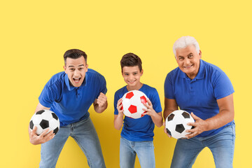 Little boy with his dad and grandfather holding soccer balls on yellow background