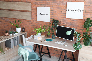Interior of stylish office with modern workplace, shelving unit and houseplants