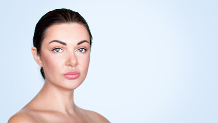 Obraz premium Beautiful girl, woman. Portrait. Collected hair. Beauty photo. Clean skin. Blue background. Looking at the camera