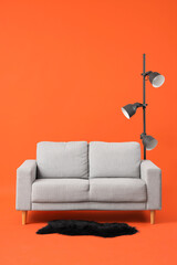 Cozy grey sofa with lamp and carpet on red background