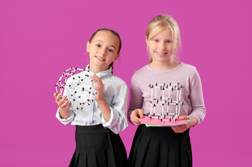 Little classmates in stylish uniform with molecular models on purple background