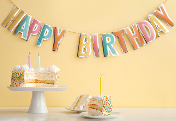 Party garland and stand with yummy Birthday cake on table near beige wall
