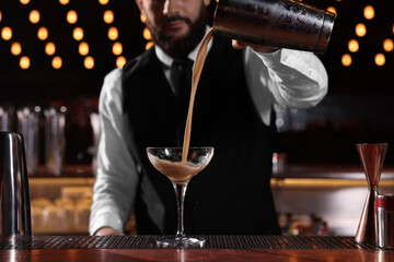 Bartender preparing Espresso Martini at bar counter, closeup. Alcohol cocktail