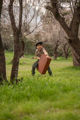 boy with a suitcase in a park
