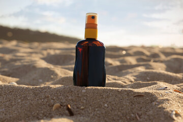 Bottle of sunscreen cream on sand at beach