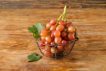 Basket with tasty ripe grapes on wooden background