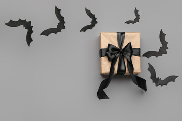 Paper bats for Halloween party and gift box on grey background