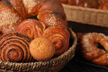 Wicker basket and different tasty freshly baked pastries on table, closeup
