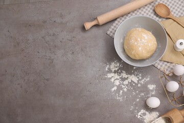 Making tasty baklava. Raw dough, eggs, flour and rolling pin on grey table, flat lay with space for text