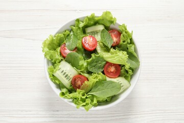 Delicious vegetable salad on white wooden table, top view
