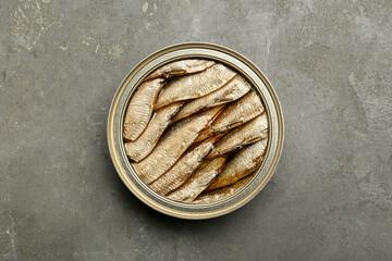 Sprats in tin can on grey textured table, top view