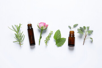 Bottles of essential oils, different herbs and rose flower on white background, flat lay